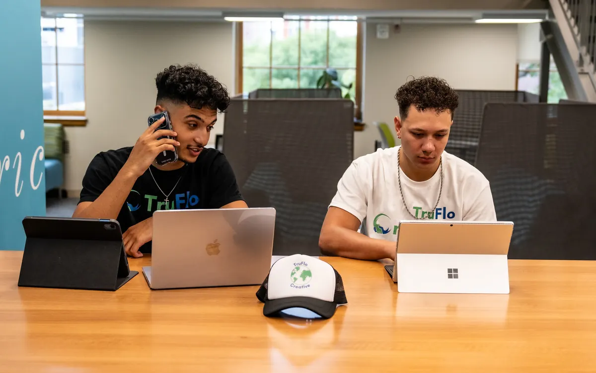 EJ Miller and Asher Fenton-Young working on laptops at a table